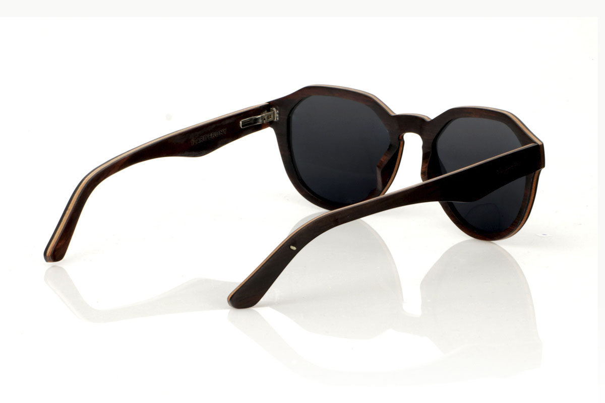 Wood eyewear of Ebony IZARO. IZARO wooden sunglasses are an expression of style and craftsmanship, made entirely of laminated ebony wood both outside and inside, with an intermediate layer of maple wood that provides a clear and striking contrast. The distinctive black and brown grain of the ebony is perfectly complemented by the distinctive hexagonal shape on the brow, while the silver metallic inlays on the sides add a touch of elegance and sophistication. With measurements of 145x50 and a caliber of 51, the IZARO are presented as a perfect option for those looking to stand out with a unique accessory that combines the natural beauty of wood with an innovative design. for Wholesale & Retail | Root Sunglasses® 